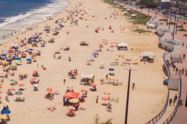 Praia de Maricá com guarda-sóis coloridos e pessoas aproveitando o dia ensolarado.