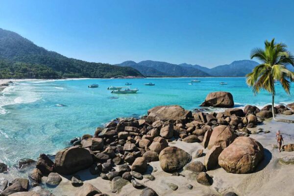 Praia do Aventureiro em Ilha Grande, com água azul turquesa e vegetação exuberante.