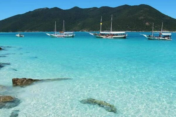Praia do Farol em Arraial do Cabo, com águas cristalinas e barcos.