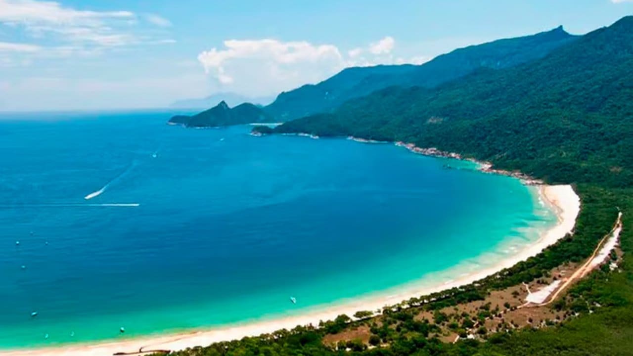 Praia paradisíaca de Ilha Grande, com águas cristalinas e montanhas ao fundo.