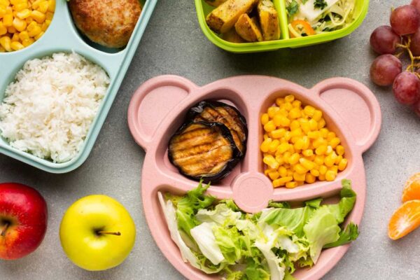 Pratos com comida infantil, incluindo milho, arroz, maçãs e uvas