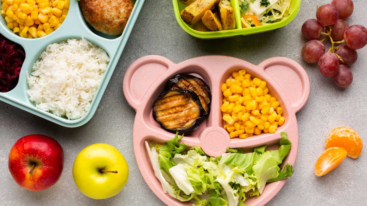 Pratos com comida infantil, incluindo milho, arroz, maçãs e uvas