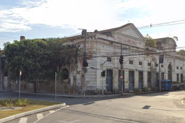 Prédio histórico em São Cristóvão em processo de deterioração, com vegetação crescendo na estrutura.