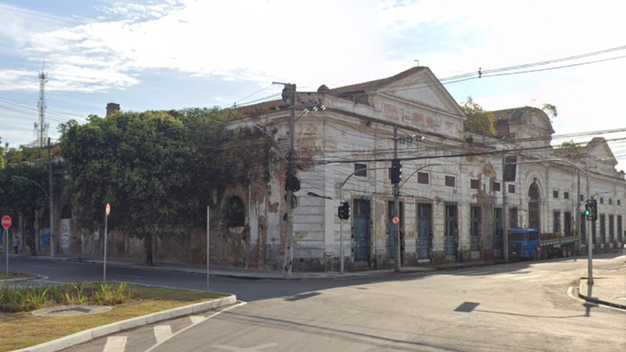 Prédio histórico em São Cristóvão em processo de deterioração, com vegetação crescendo na estrutura.