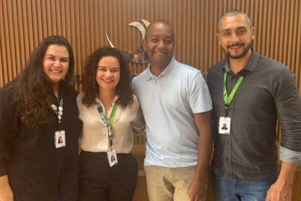 Quatro pessoas sorrindo, duas mulheres e dois homens, em um evento com identificação visual do INEA, recebendo um prêmio por um projeto sustentável.
