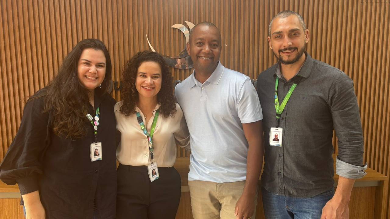 Quatro pessoas sorrindo, duas mulheres e dois homens, em um evento com identificação visual do INEA, recebendo um prêmio por um projeto sustentável.