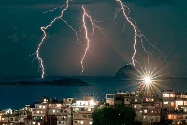Raios iluminam o céu sobre cidade costeira, capturados por Igor Albuquerque.