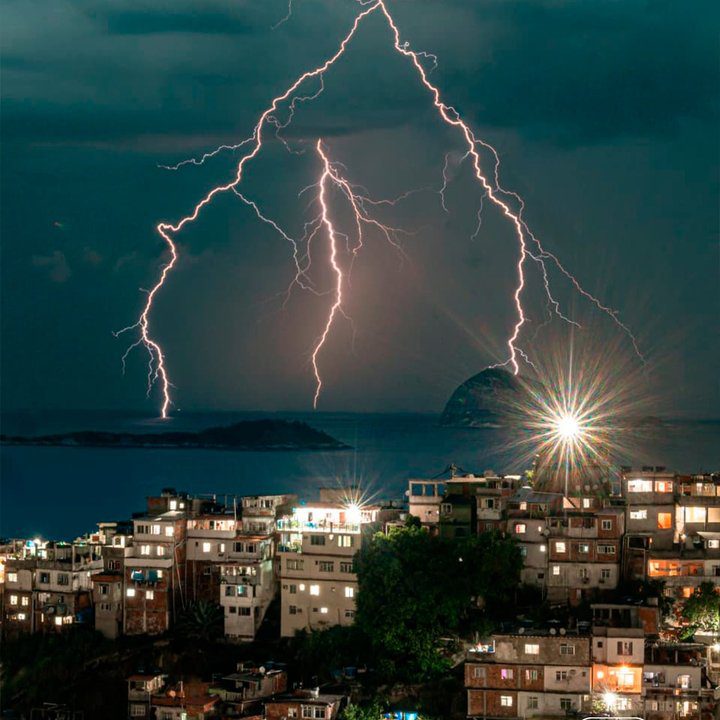 Raios iluminam o céu sobre cidade costeira, capturados por Igor Albuquerque.