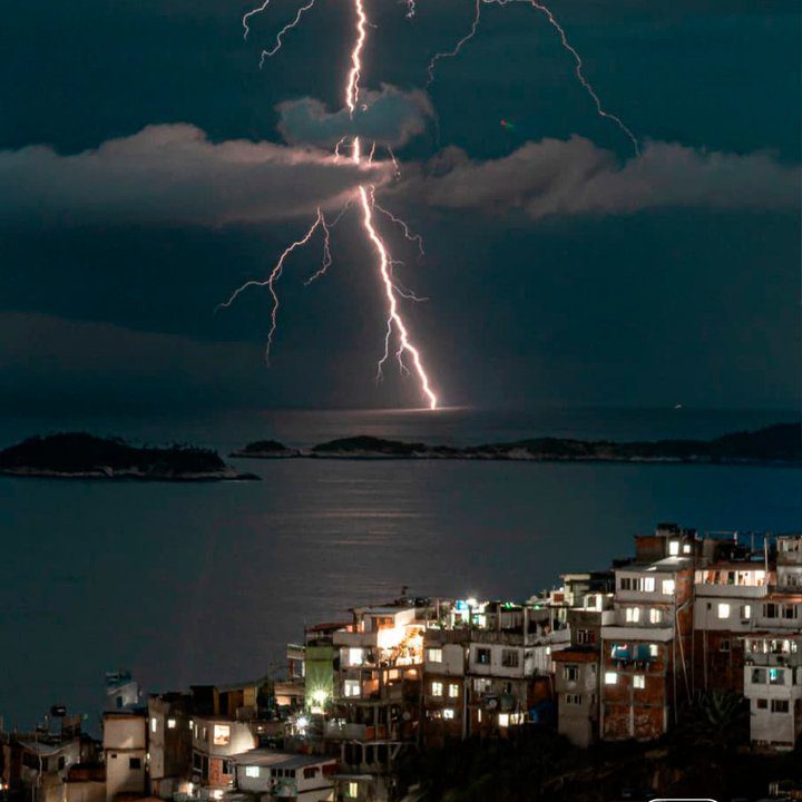Raios iluminam o céu sobre o mar e a cidade, capturados por Igor Albuquerque.