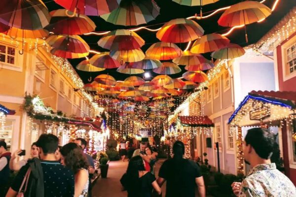 Rua decorada com guarda-chuvas coloridos e luzes para celebração noturna.