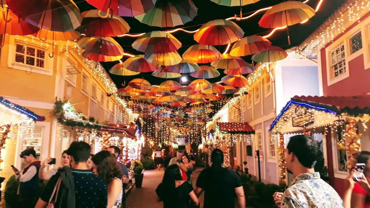 Rua decorada com guarda-chuvas coloridos e luzes para celebração noturna.
