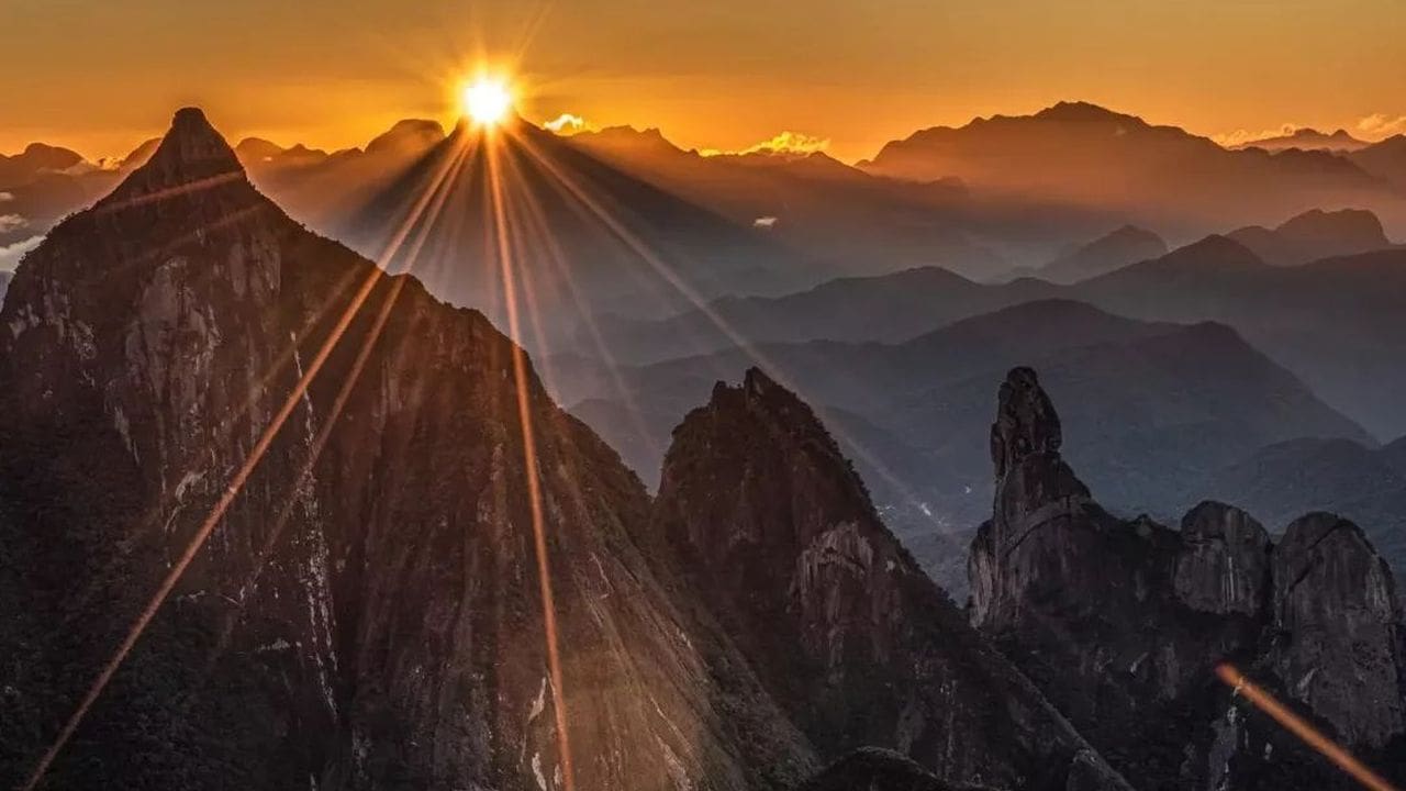 Serra dos Órgãos, Dedo de Deus, com o sol nascendo, raios solares e montanhas.