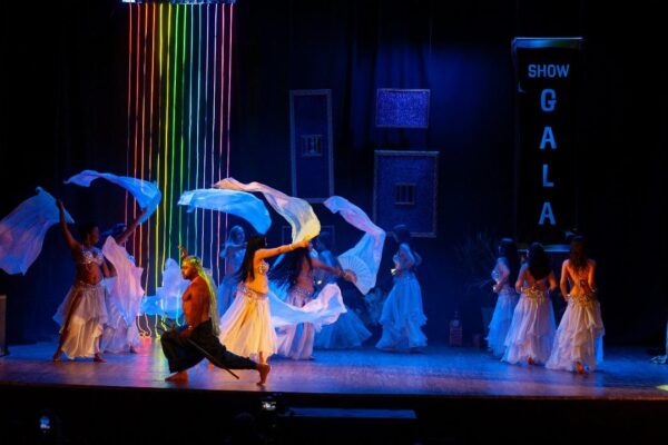 Show de gala EFDO 2024, dançarinas com véus e luzes coloridas no palco