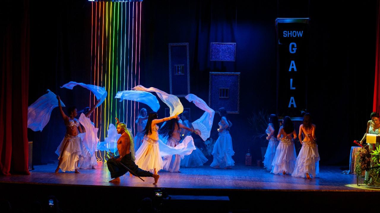 Show de gala EFDO 2024, dançarinas com véus e luzes coloridas no palco