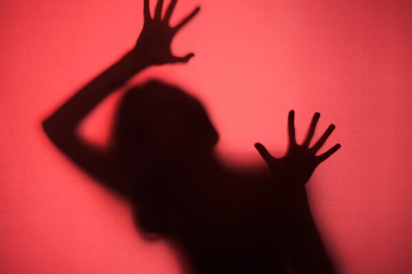 Sombra de pessoa com mãos na frente de superfície vermelha