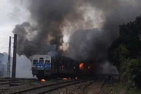 Trem em chamas em pátio da estação Japeri, com fumaça densa.