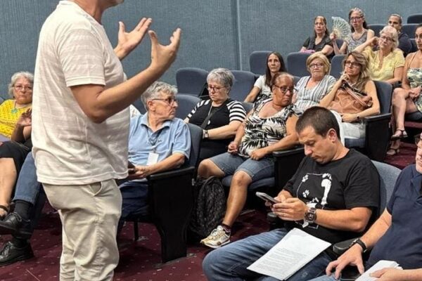 Um homem fala para um grupo de pessoas sentadas em um auditório, a maioria mulheres, durante uma reunião sobre a proteção animal.