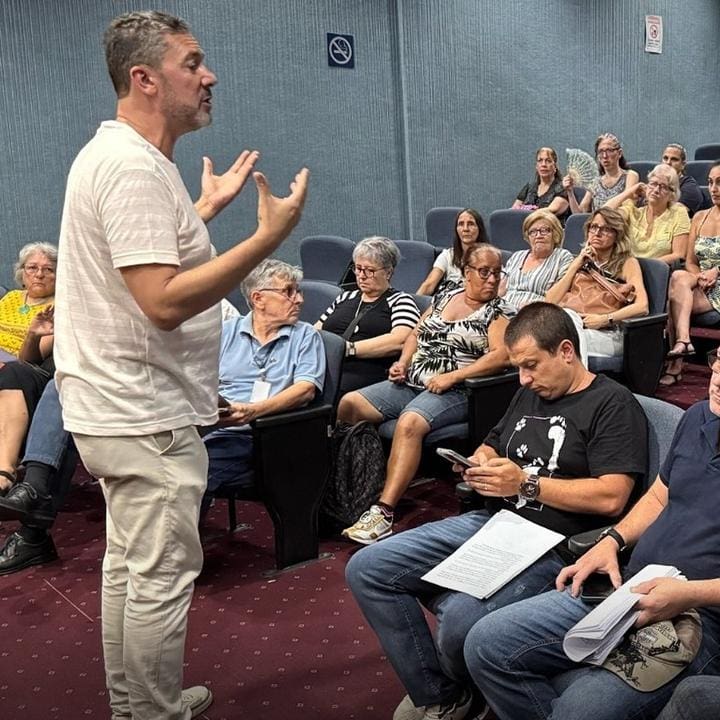 Um homem fala para um grupo de pessoas sentadas em um auditório, a maioria mulheres, durante uma reunião sobre a proteção animal.