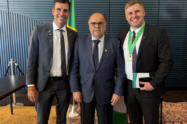 Vereador Maicon Gonçalves recebe honraria em Brasília. Três homens em trajes formais, com destaque para a medalha.