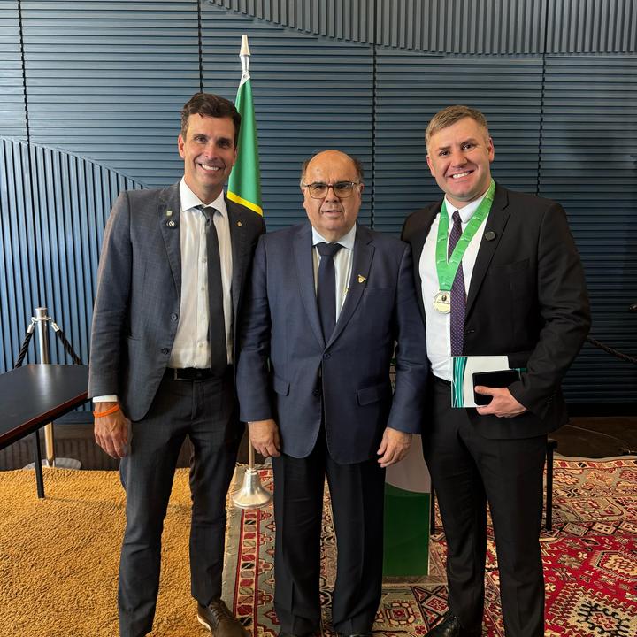Vereador Maicon Gonçalves recebe honraria em Brasília. Três homens em trajes formais, com destaque para a medalha.