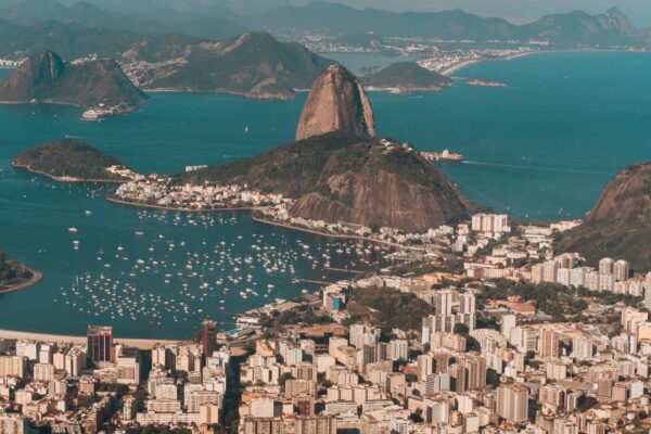 Vista aérea da Baía de Guanabara com o Pão de Açúcar e a cidade do Rio de Janeiro ao fundo.