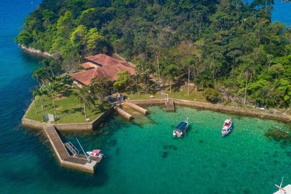 Vista aérea da costa de Paraty com ilha, casas, barcos e águas cristalinas