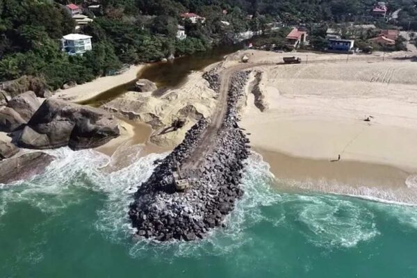 Vista aérea da Praia do Recanto em Maricá, com quebra-mar e obras na areia.