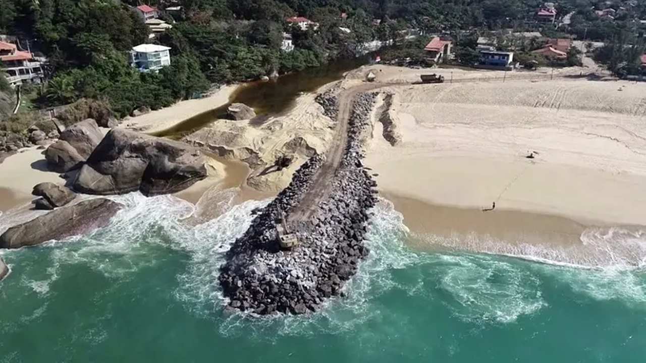 Vista aérea da Praia do Recanto em Maricá, com quebra-mar e obras na areia.