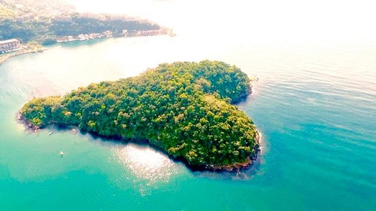 Vista aérea da Praia do Sossego em Niterói, com vegetação exuberante e águas cristalinas.
