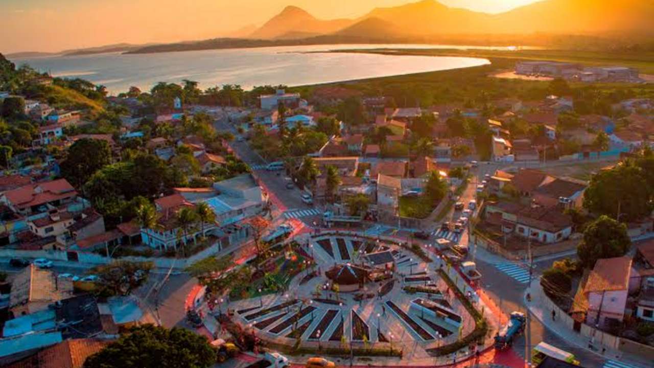 Vista aérea de Maricá, Costa do Sol, com lago e cidade ao pôr do sol.