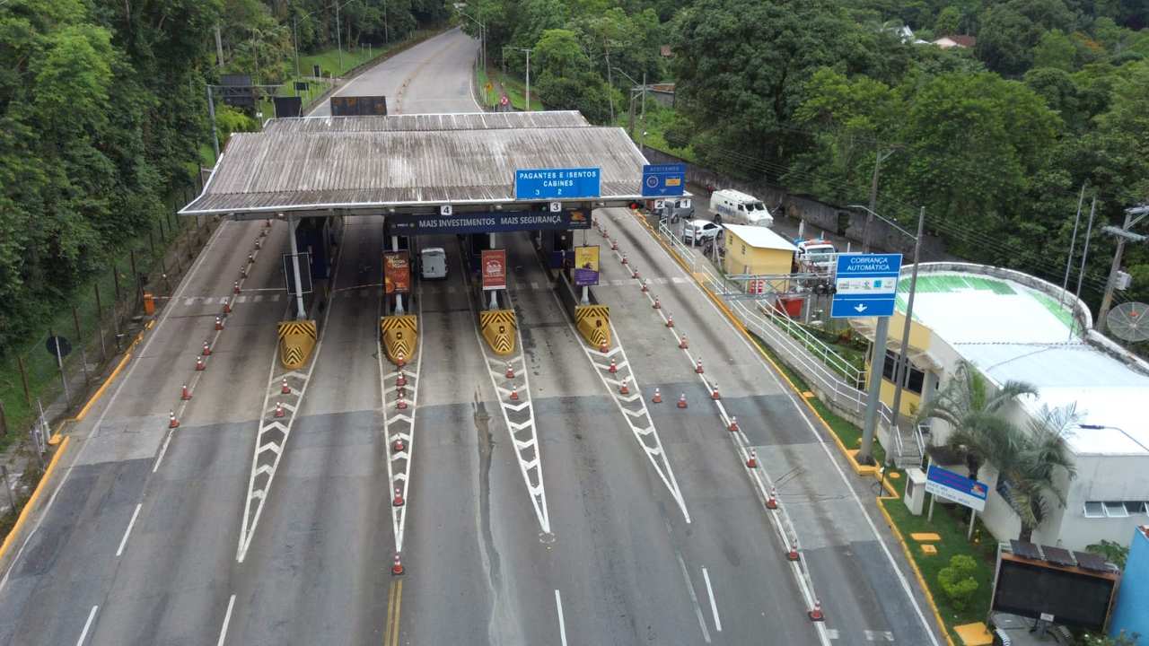 Vista aérea de praça de pedágio com cabines e sinalização.