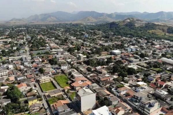 Vista aérea de Seropédica, com edifícios residenciais e montanhas ao fundo.