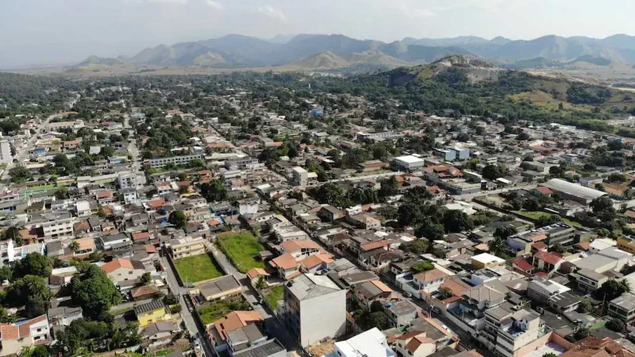 Vista aérea de Seropédica, com edifícios residenciais e montanhas ao fundo.