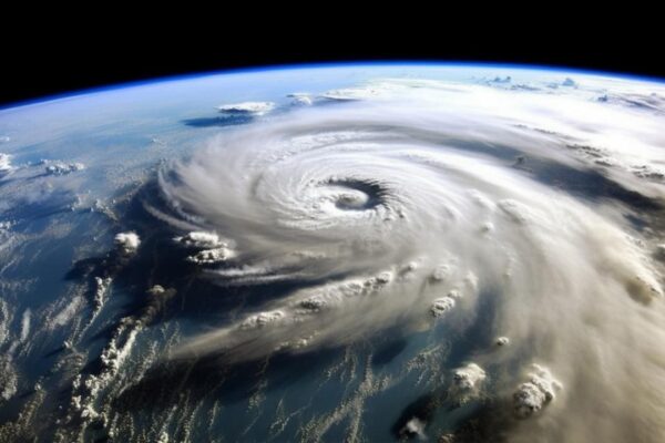 Vista aérea de um ciclone extratropical sobre o oceano, com vórtice proeminente e céu azul.