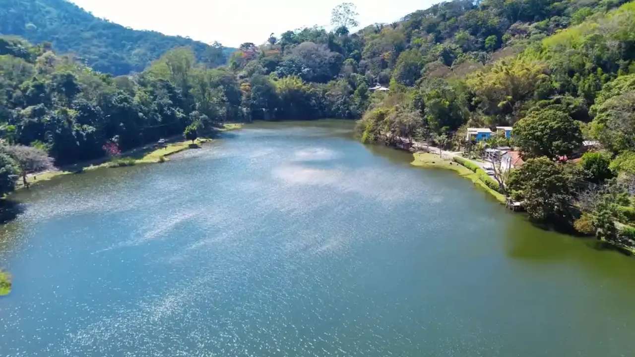 Vista aérea do Lago do Caiçara, em Barra do Piraí, com vegetação exuberante e construções.