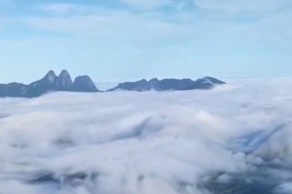 Vista aérea do Pico do Caledônia com mar de nuvens e os Três Picos ao fundo