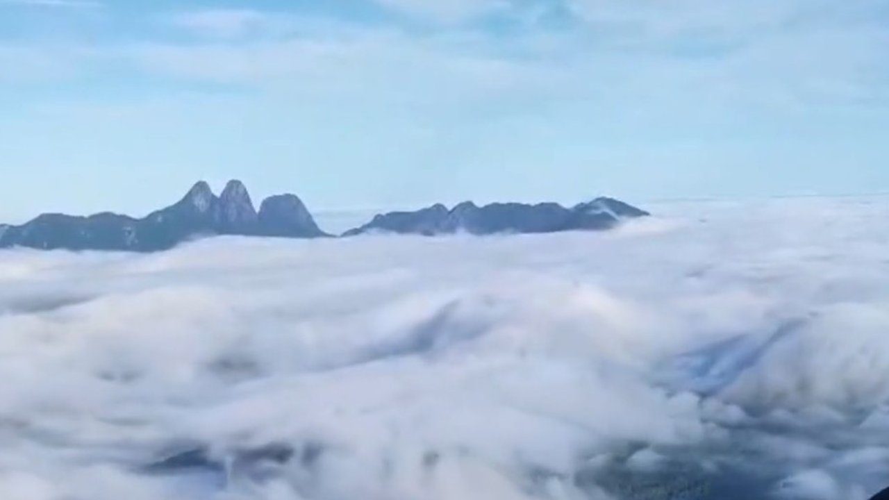 Vista aérea do Pico do Caledônia com mar de nuvens e os Três Picos ao fundo