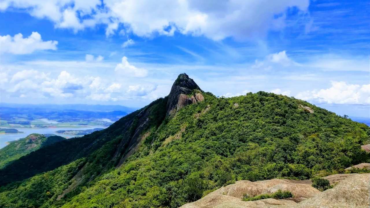 Vista deslumbrante da Pedra das Flores em São José do Vale do Rio Preto, com céu azul e vegetação exuberante.