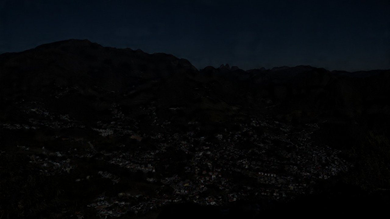 Vista noturna de Nova Friburgo com bairros escuros devido à falta de energia.