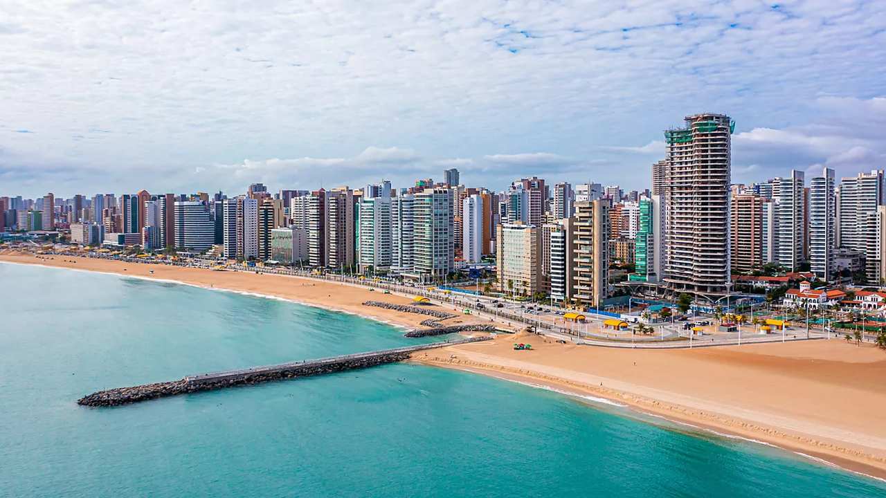 Vista panorâmica da orla de Fortaleza, com edifícios modernos e praia.
