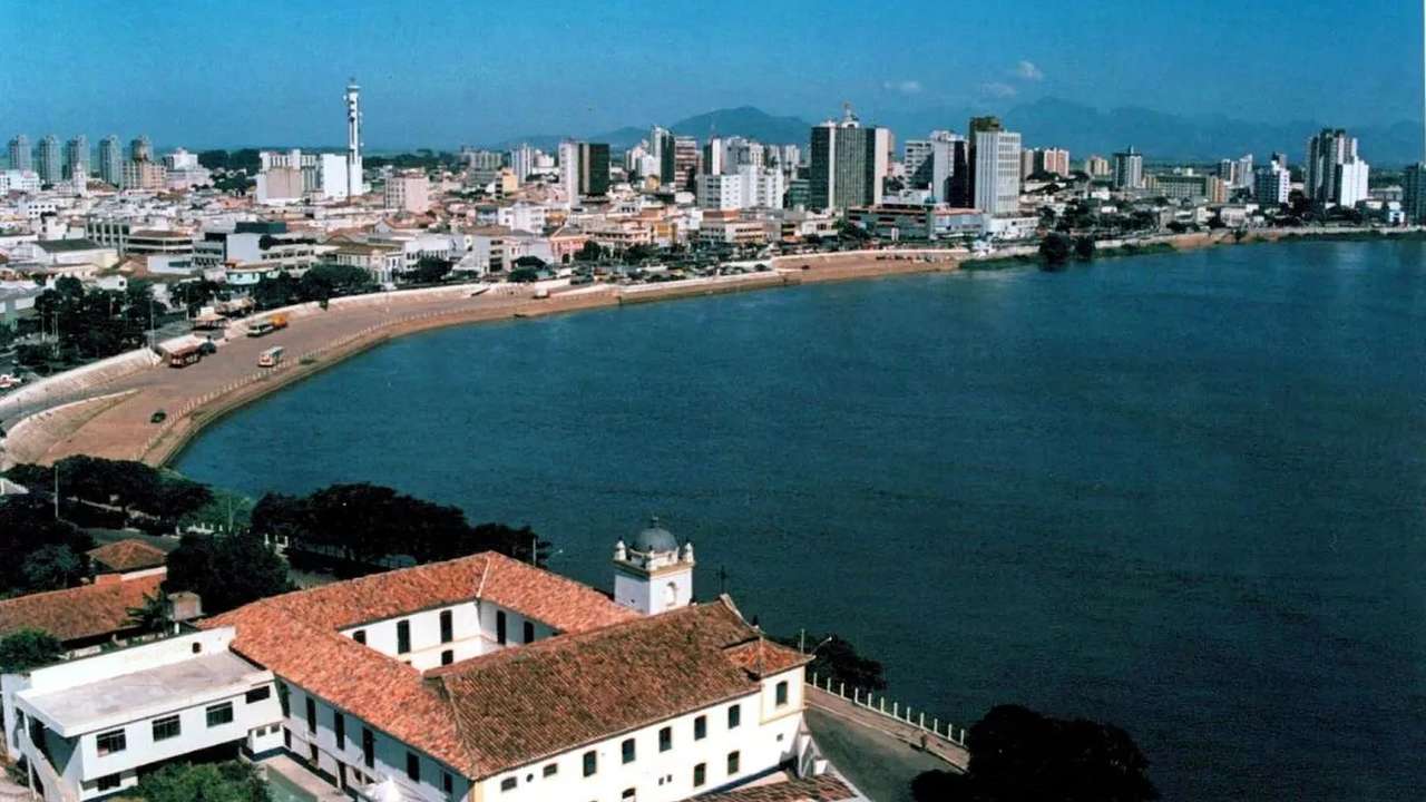 Vista panorâmica de Campos dos Goytacazes, com edifícios e o rio.