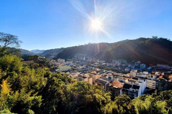 Vista panorâmica de Nova Friburgo, com prédios, montanhas e céu ensolarado