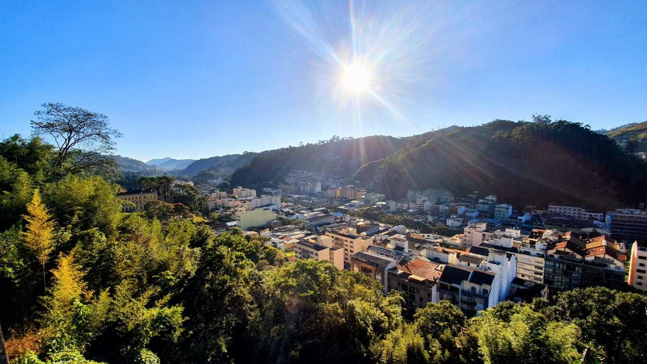 Vista panorâmica de Nova Friburgo, com prédios, montanhas e céu ensolarado