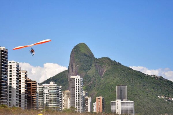 Voo de parapente sobre o Rio de Janeiro, com montanha e prédios ao fundo