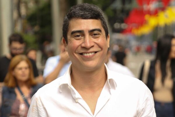 Wanderson Nogueira sorrindo em meio a pessoas, em um evento ao ar livre.