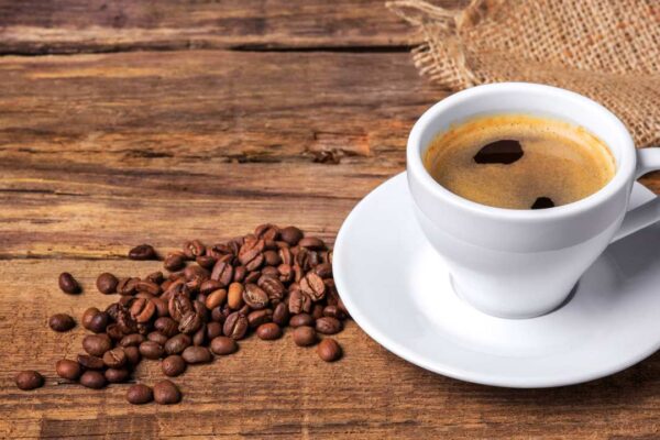 Xícara de café com grãos e fundo rústico de madeira. Apreensão de café falsificado no Rio.