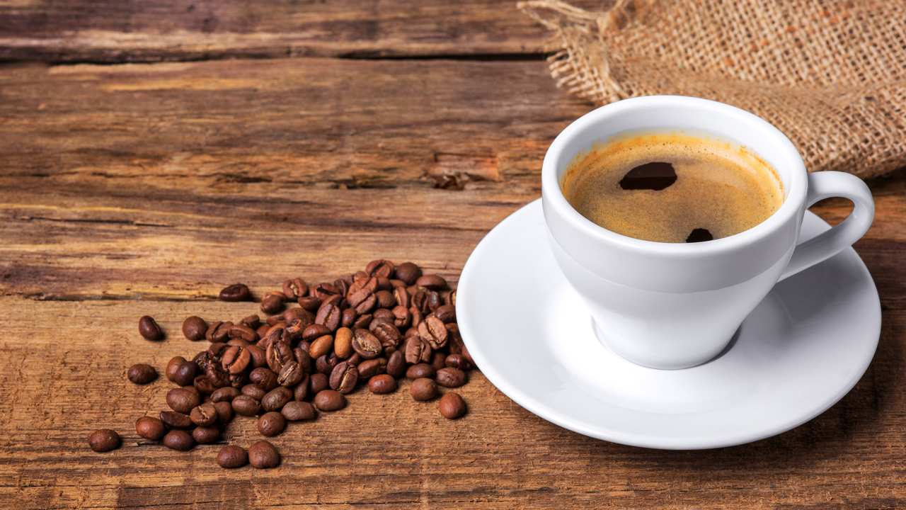 Xícara de café com grãos e fundo rústico de madeira. Apreensão de café falsificado no Rio.