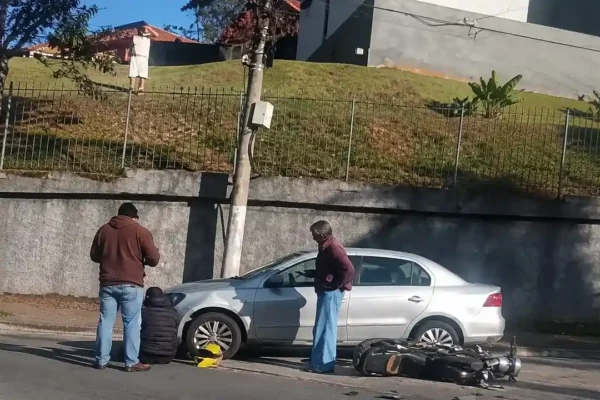 Motocicleta caída no asfalto ao lado de um carro após acidente na subida do Catarcione, em Nova Friburgo.