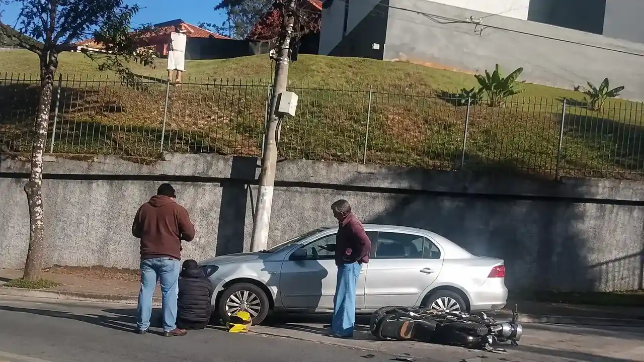 Motocicleta caída no asfalto ao lado de um carro após acidente na subida do Catarcione, em Nova Friburgo.