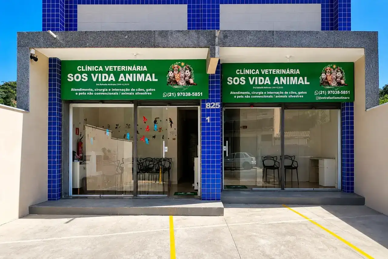 A imagem mostra a fachada da Clínica Veterinária SOS Vida Animal, instalada em um prédio moderno de dois pavimentos. A entrada possui ampla fachada de vidro, placas verdes com a identidade visual da clínica e estacionamento em frente ao imóvel.